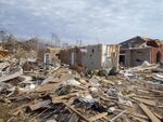 EF3 damage example-- The majority of the house was heavily damaged, with some trees uprooted in the background. Only a portion of a wall remains. Debris is scattered at the site of impact.