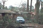 F0 damage to a home in Georgia from a tornado on March 13, 1997. There is only minor scuffing to the roof. Alongside the roof damage, several trees appear to have been uprooted, with some large branches scattered around the driveway.