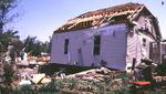 F1 damage to a home from a tornado on May 30, 1998, in South Dakota. The only major point of damage is the roof, with only the skeleton remaining. Some siding of the house has been peeled off, with debris scattered; the house has also been shifted off its foundation slightly.